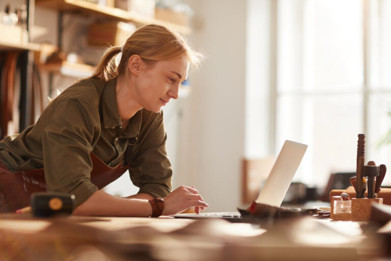 woman smiling at laptop in shop