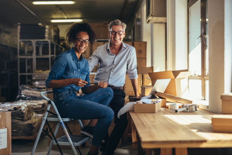 man and woman smiling at camera in warehouse