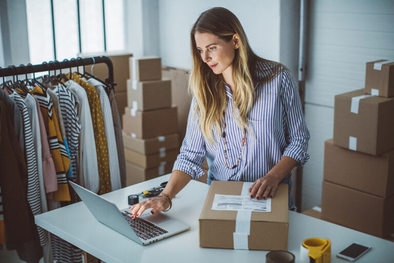 woman with package looking at laptop