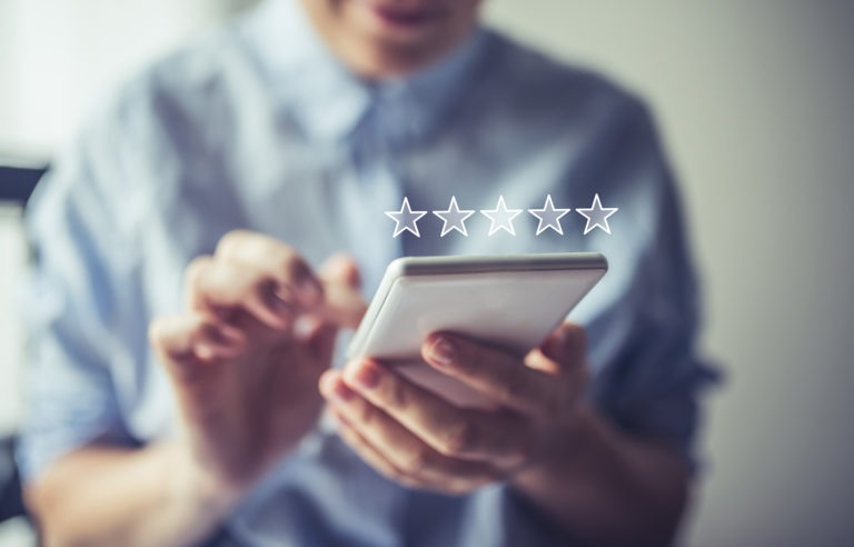 man holding mobile smiling with 5 star rating