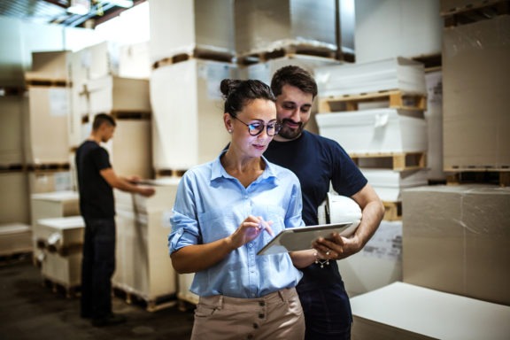 woman and man in warehouse looking at tablet
