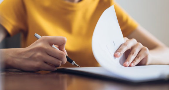 woman writing on paper at desk close up