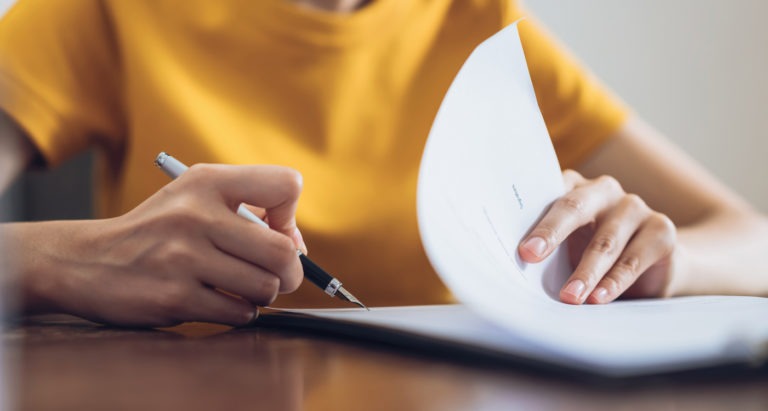 woman writing on paper at desk close up