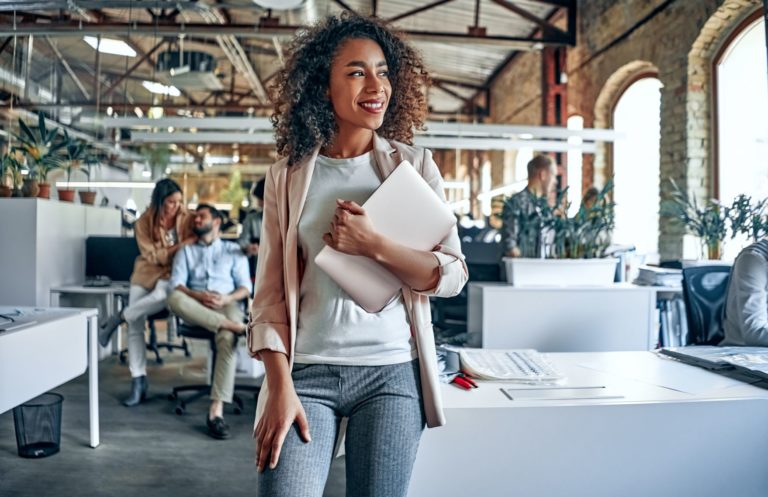 woman clutching laptop smiling in office