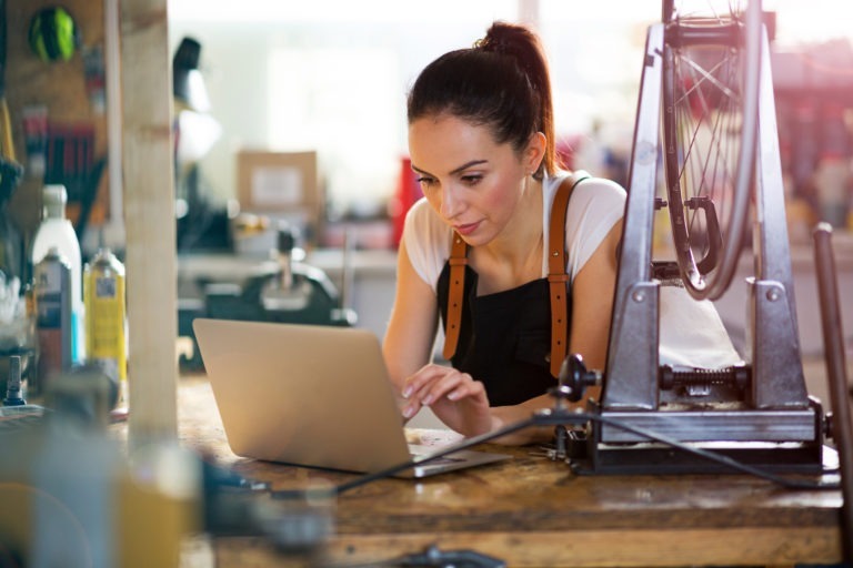 woman in bike repair shop on laptop