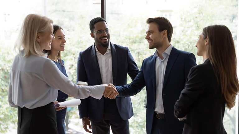 a group of people standing around smiling and shaking hands