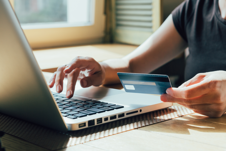 person holding a credit card typing on a computer