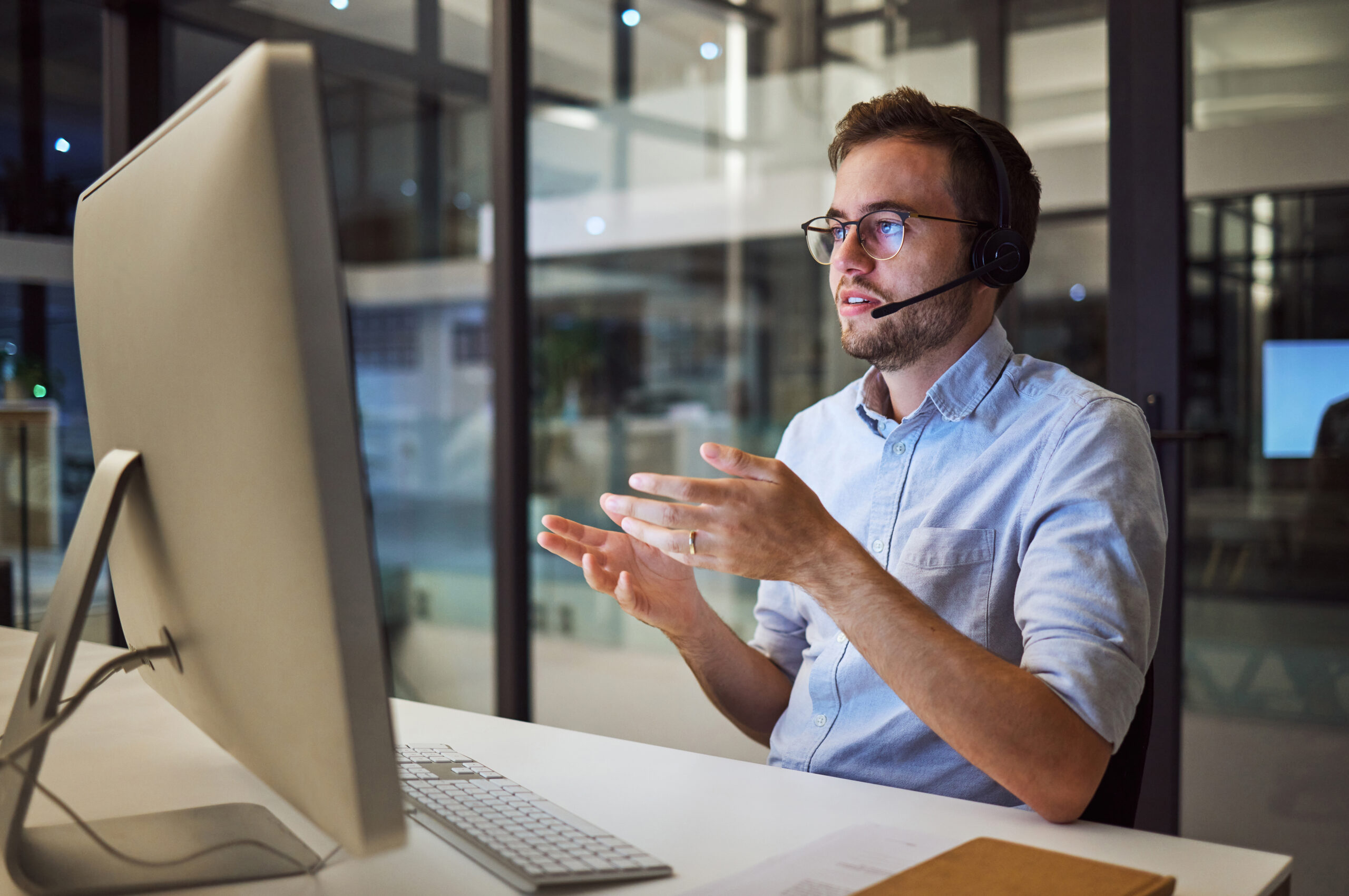 man sitting at a computer talking wearing a headset