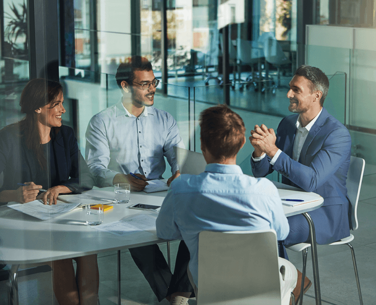 4 people sitting around a table working together and laughing