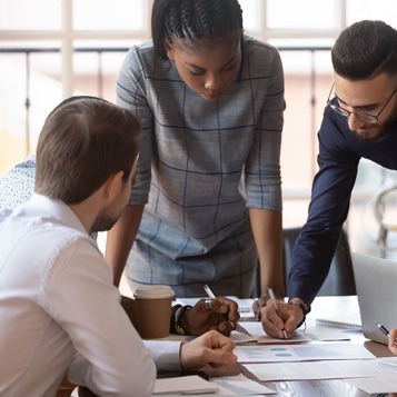 4 people gathered around a table looking and pointing at notes