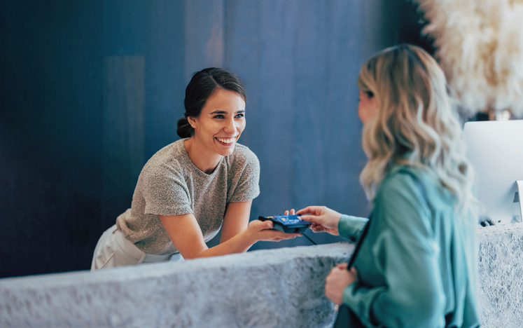 woman making card payment while talking with another woman