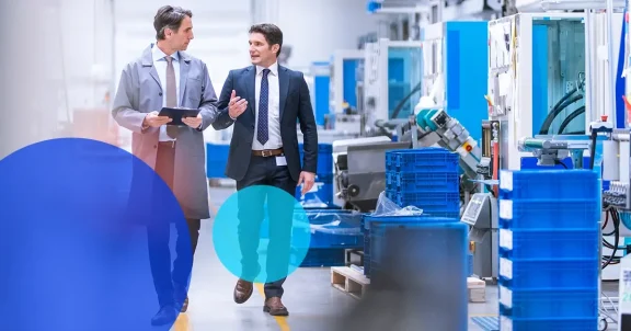 two professional men walking through a manufacturing facility