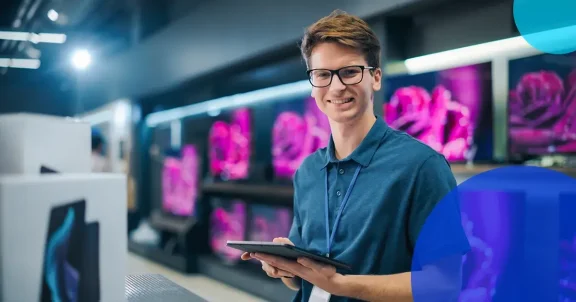 Smiling retail associate at electronics store standing with tablet