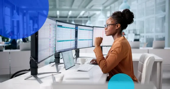 professional woman looking at monitors at her desk.